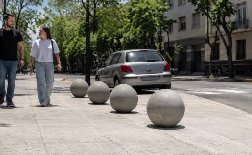 Bolas de cemento delimitan la vereda y protegen el espacio peatonal en una esquina de la Ciudad de Buenos Aires.