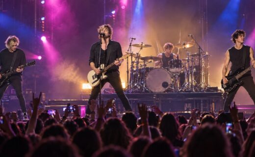 5 Seconds of Summer durante un recital con luces de colores y público en el Movistar Arena de Buenos Aires.