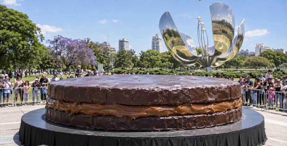 Alfajor gigante cubierto de chocolate frente a la Floralis Genérica, rodeado de público en la Plaza de las Naciones Unidas de Recoleta.