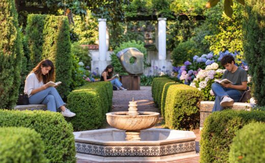 Tres jóvenes leen en el Jardín Andaluz del Museo Larreta, junto a una fuente rodeada de vegetación.