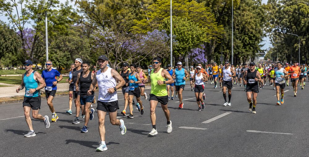 Corredores de la Maratón de Buenos Aires 42K avanzan por una avenida arbolada de Palermo.