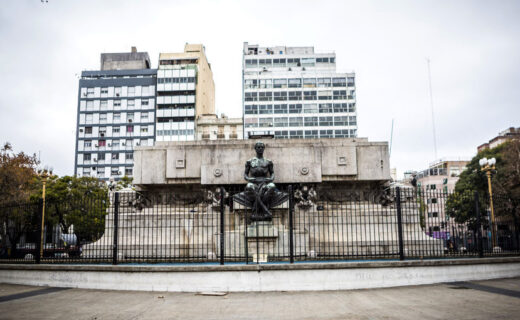 Mausoleo de Bernardino Rivadavia visto de frente en Plaza Miserere, con su escultura de bronce y los edificios de Once al fondo.
