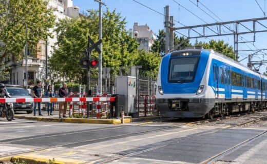Tren Sarmiento atravesando un paso a nivel con la barrera baja y un nuevo sistema de monitoreo ferroviario.