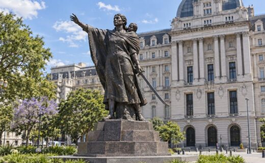Monumento a Juana Azurduy en la Plaza del Correo, con el Palacio Libertad y la vegetación del Bajo porteño de fondo.