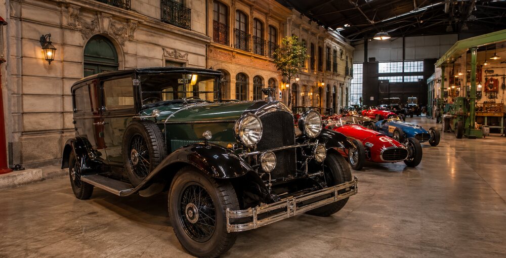 Automóviles clásicos exhibidos en una ambientación histórica del Museo del Automóvil de Villa Real.