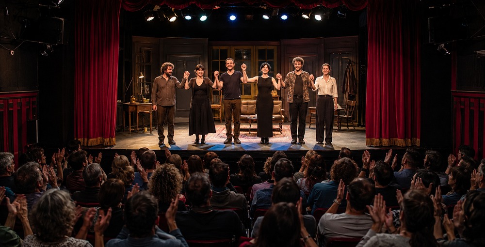 Elenco de una obra de teatro saluda sobre el escenario ante el aplauso del público en una sala de Buenos Aires.