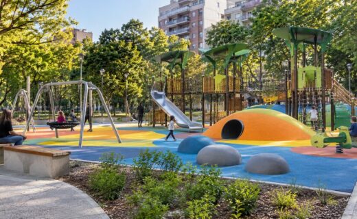 Patio de juegos renovado de Plaza Almagro con mangrullos, hamacas, suelo de colores y familias disfrutando del espacio verde.