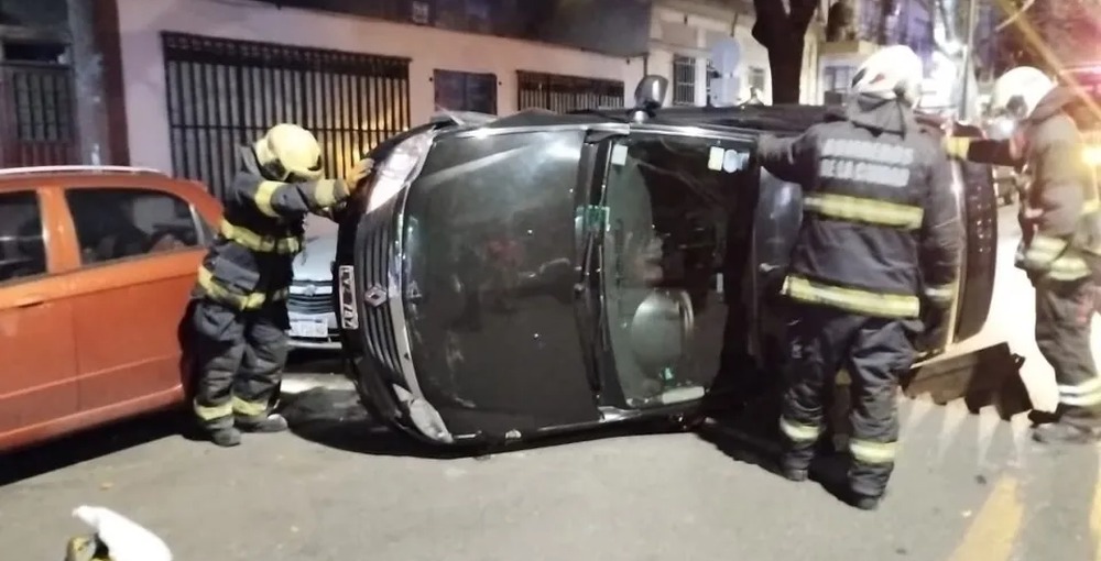 Bomberos trabajan junto a un auto volcado de costado tras el choque en Cabildo y Manuela Pedraza, donde una persona resultó herida.
