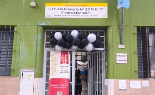 Fachada de la escuela Pedro Medrano de Villa Devoto, decorada con globos y un cartel conmemorativo por sus 100 años de educación e historia.