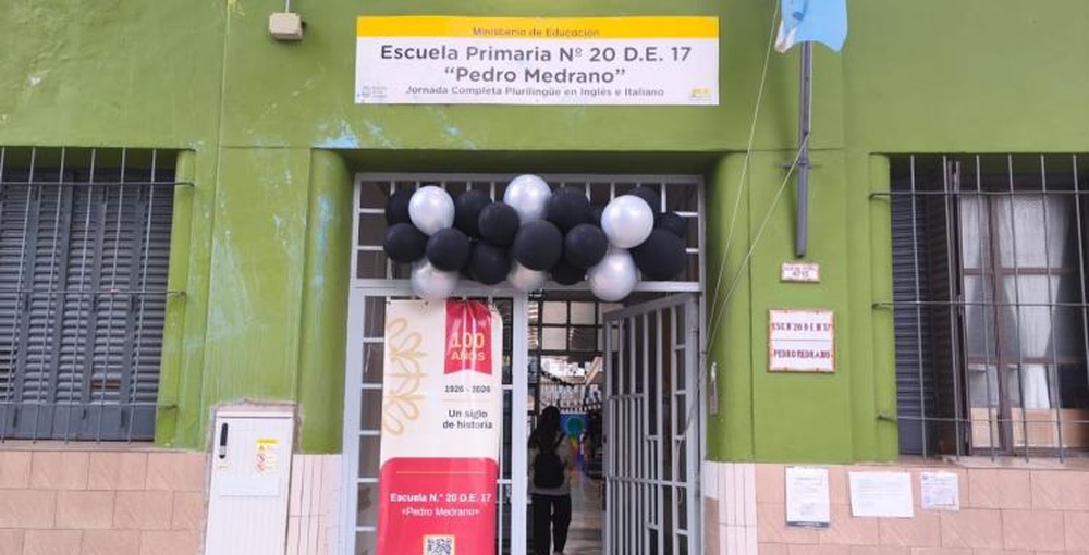 Fachada de la escuela Pedro Medrano de Villa Devoto, decorada con globos y un cartel conmemorativo por sus 100 años de educación e historia.