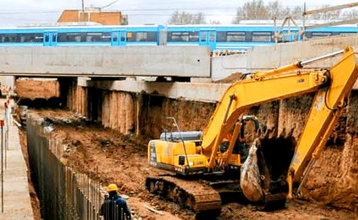 Obras del paso bajo nivel Irigoyen en Villa Luro, con una excavadora y un tren Sarmiento, donde los vecinos podrán elegir el nombre del túnel.